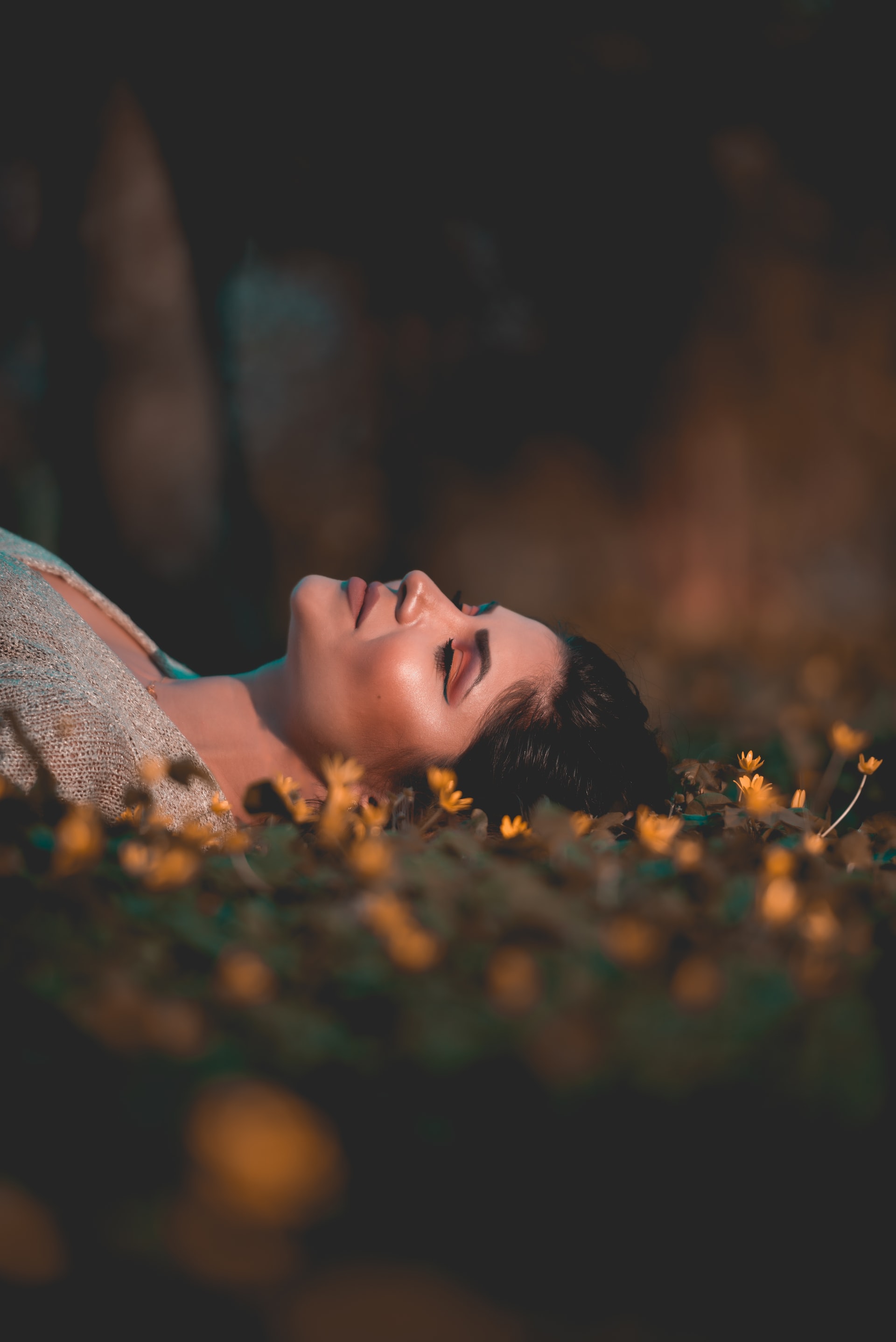 A woman laying in a field, surrounded by flowers, deep in hypnosis.